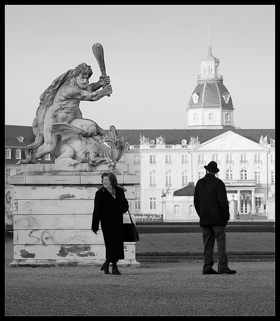 couple in plaza underneath sculpture